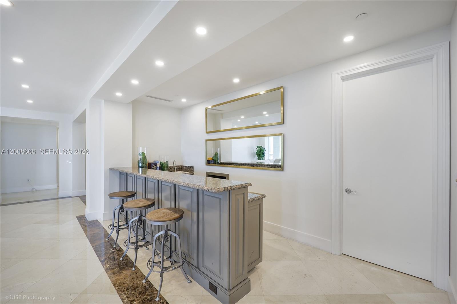 A home bar features a granite countertop, gray cabinetry, three stools, and two wall mirrors — 3400 SW 27th Ave # 2202, Miami FL 33133, MIAMI, FL