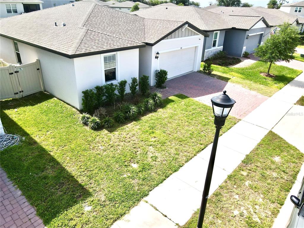 An elevated view of a suburban house exterior with a paved driveway and front lawn — 909 CAMBRIDGE DRIVE, WINTER HAVEN, FL