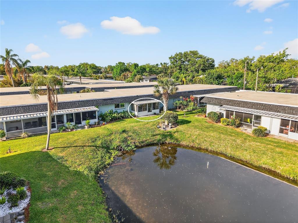 An exterior view of a single-story apartment building with a screened-in patio near a pond — 4160 FRUITVILLE ROAD UNIT 11, SARASOTA, FL
