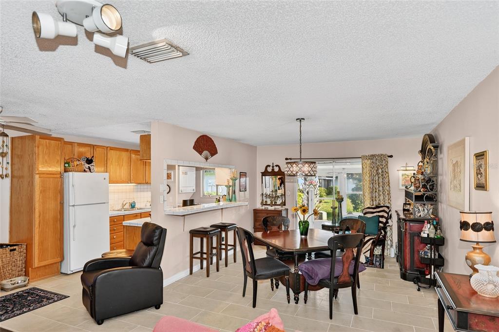 A dining area and kitchen with light tile floors, wooden cabinets, and a breakfast bar — 4160 FRUITVILLE ROAD UNIT 11, SARASOTA, FL