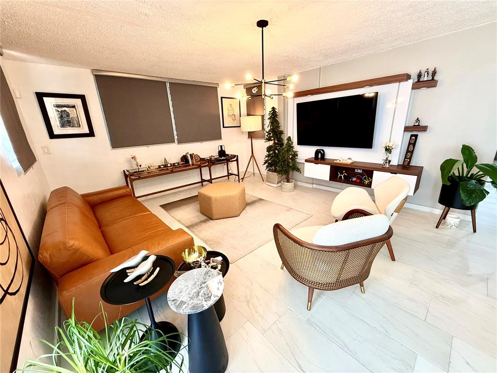 A modern living room features a leather sofa, two accent chairs, and a wall-mounted television — B8 CALLE 8 LAGO URB ALTAMIRA, FAJARDO, PR