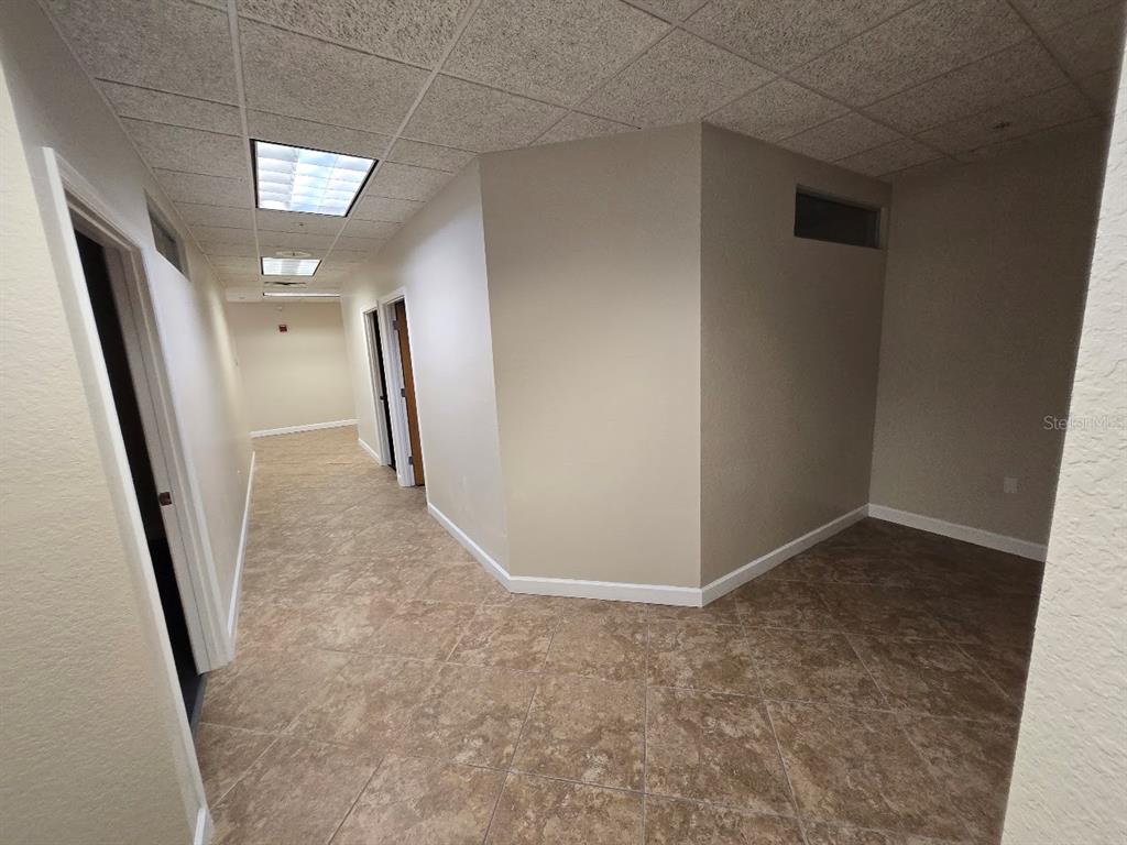 An interior hallway with beige walls, tile flooring, and a drop ceiling with recessed lighting — 5218 4TH AVENUE CIRCLE E, BRADENTON, FL