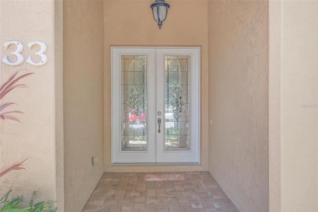A front entryway features double glass-paneled doors, a hanging light fixture, and paver flooring — 33 MARSHVIEW LANE, PALM COAST, FL