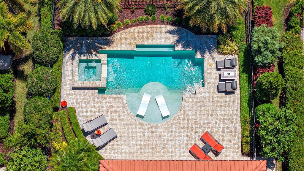 An aerial view of a backyard swimming pool with a spa and surrounding paver patio — 7975 MATERA COURT, LAKEWOOD RANCH, FL