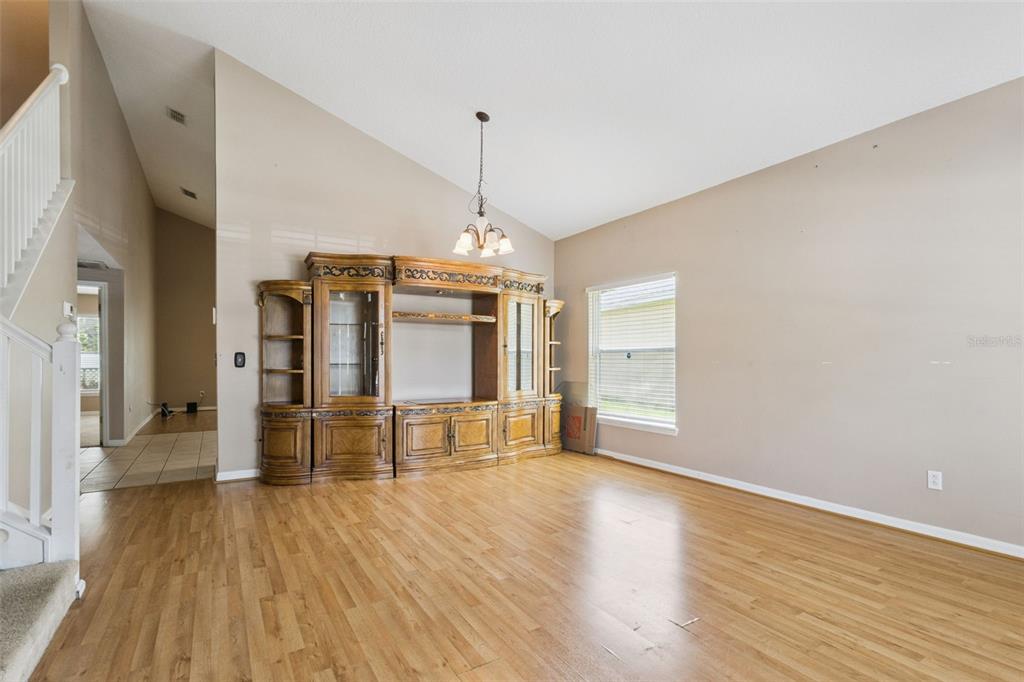 A living room with light wood floors, a large wooden entertainment center, and vaulted ceilings — 435 SCRUB JAY WAY, DAVENPORT, FL