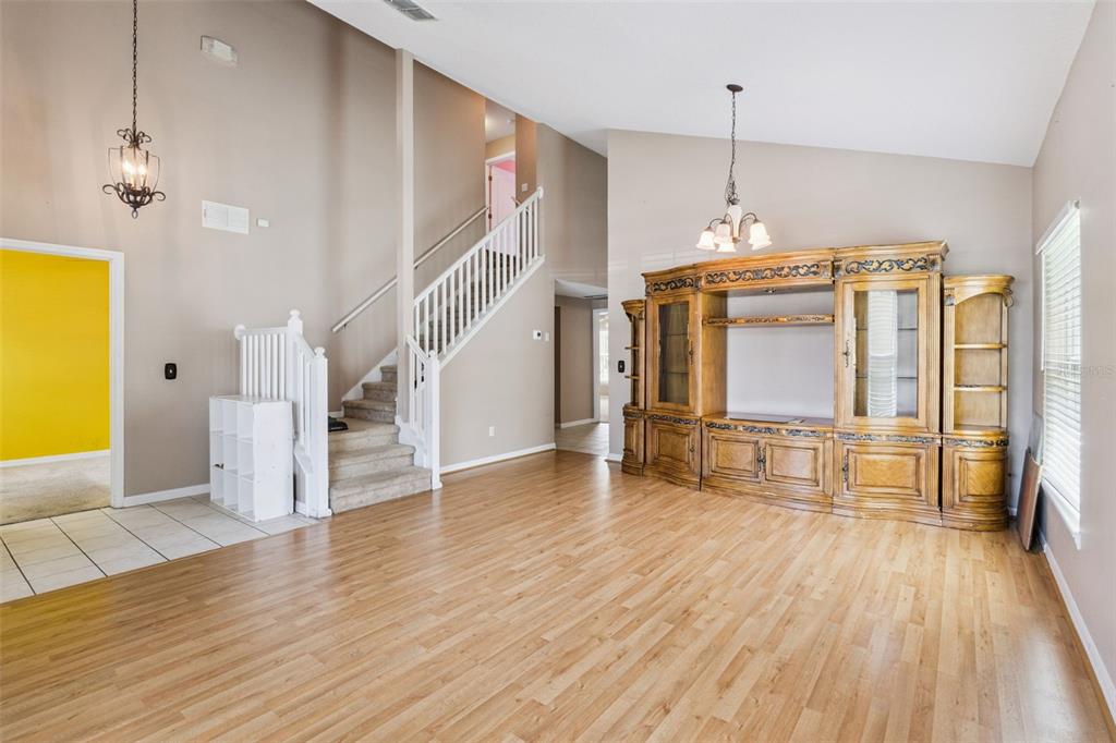 A living room features light wood flooring, a staircase, and a large wooden entertainment center — 435 SCRUB JAY WAY, DAVENPORT, FL