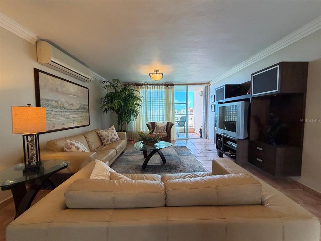 A living room features two leather sofas, a glass coffee table, and a balcony view — PR3 CARR. PUERTO DEL REY UNIT PC2, CEIBA, PR