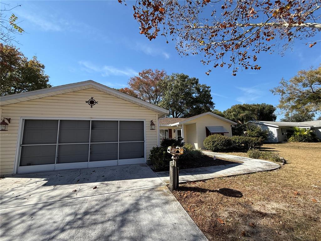 A single-story house with light yellow siding, a two-car garage, and a concrete driveway — 10800 SW 62ND AVENUE, OCALA, FL