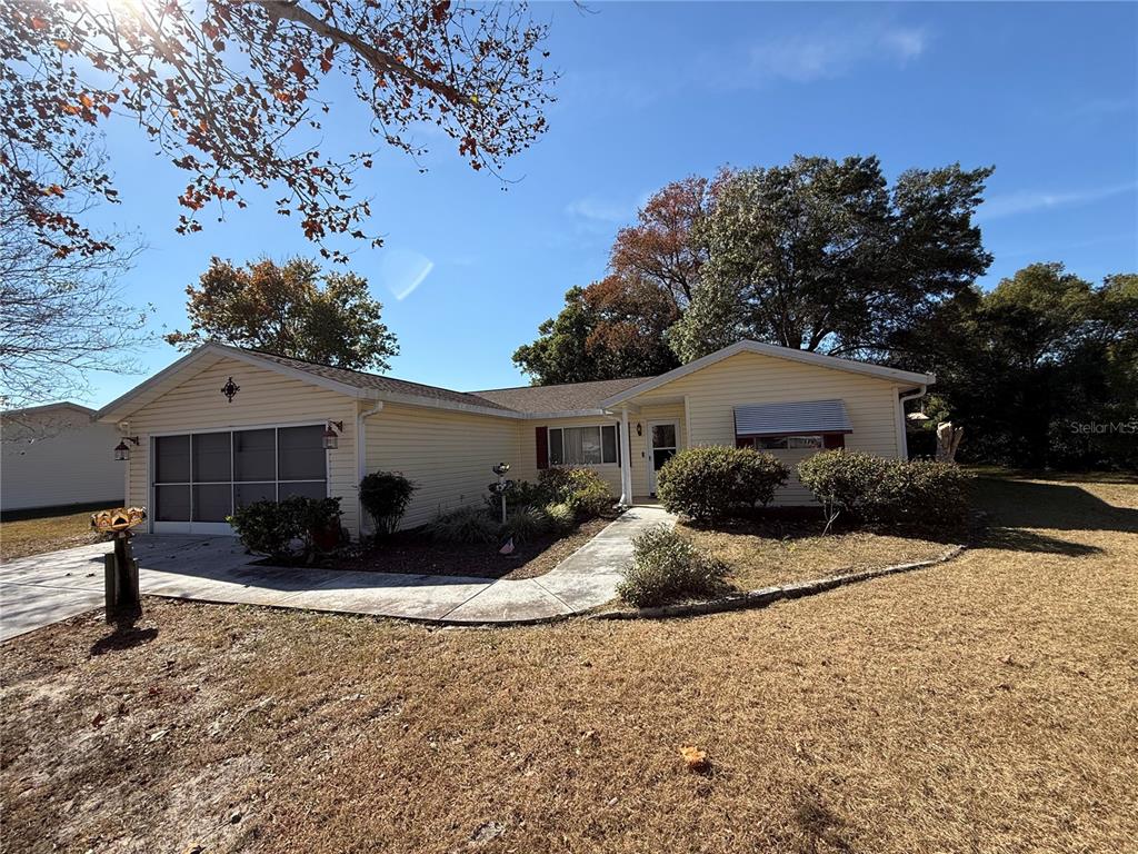 A single-story house with light yellow siding, a garage, and a concrete walkway — 10800 SW 62ND AVENUE, OCALA, FL
