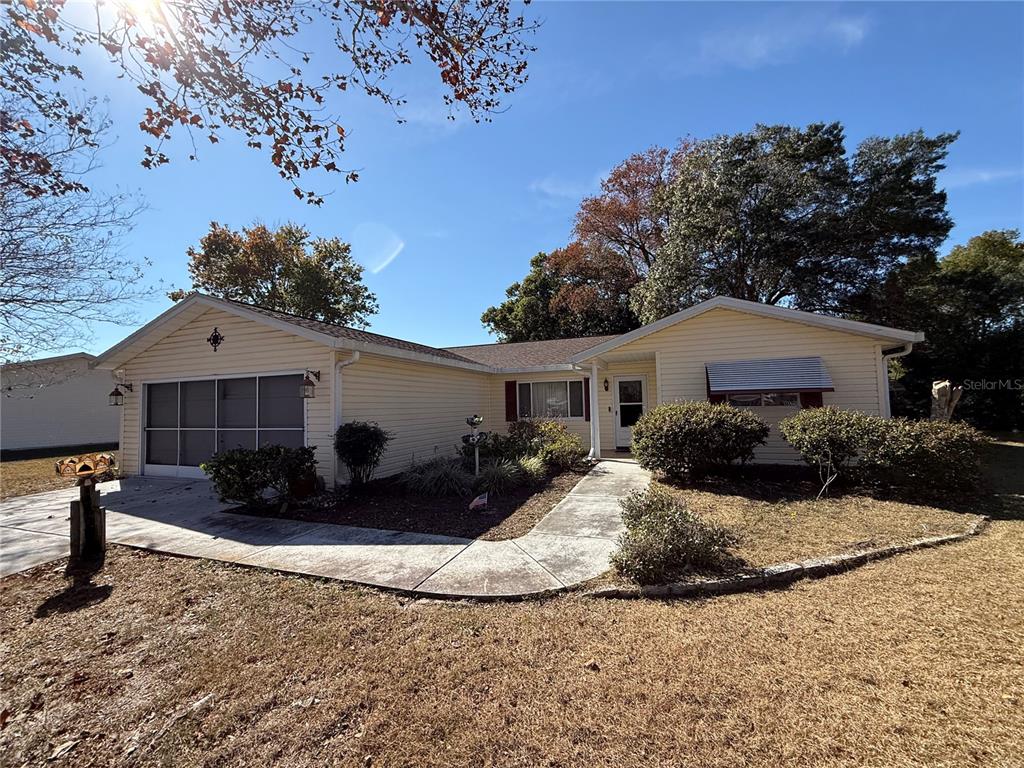A single-story house with light yellow siding, a garage, and a concrete walkway — 10800 SW 62ND AVENUE, OCALA, FL