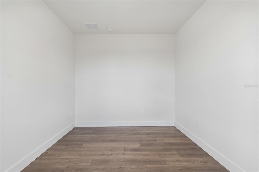 An empty room with white walls and dark wood-look flooring — 2856 MARRAKESH LANE, SARASOTA, FL