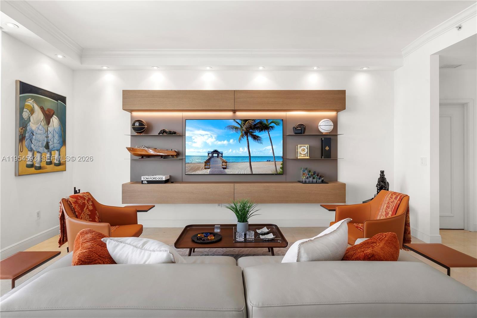 A modern living room features a wall-mounted television unit, orange armchairs, and a gray sofa — 901 Brickell Key Blvd # 3706, Miami FL 33131, MIAMI, FL