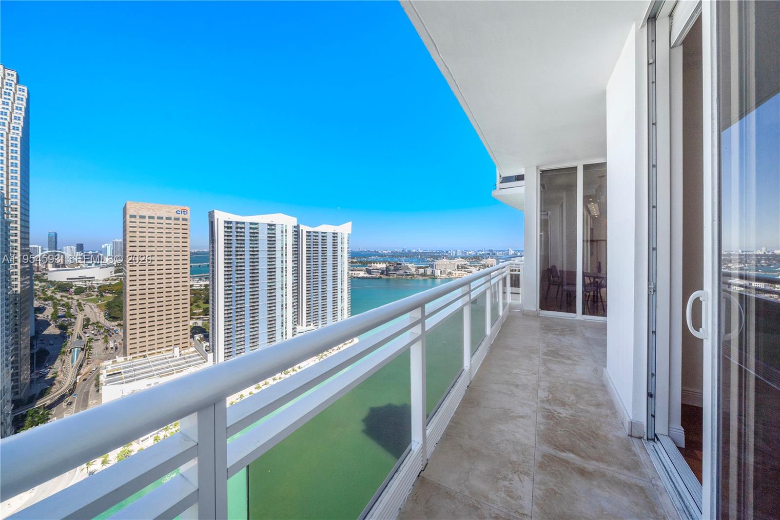 A high-rise balcony with a glass railing overlooks a city skyline and a bay — 901 Brickell Key Blvd # 3706, Miami FL 33131, MIAMI, FL