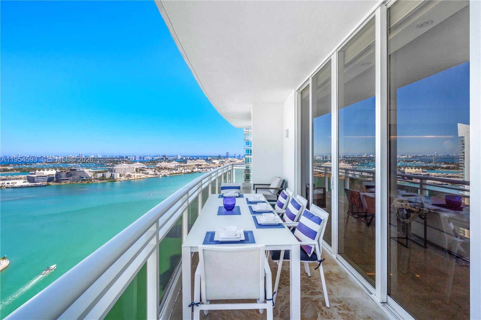 A balcony with a dining table overlooks a bay and a city skyline — 901 Brickell Key Blvd # 3706, Miami FL 33131, MIAMI, FL