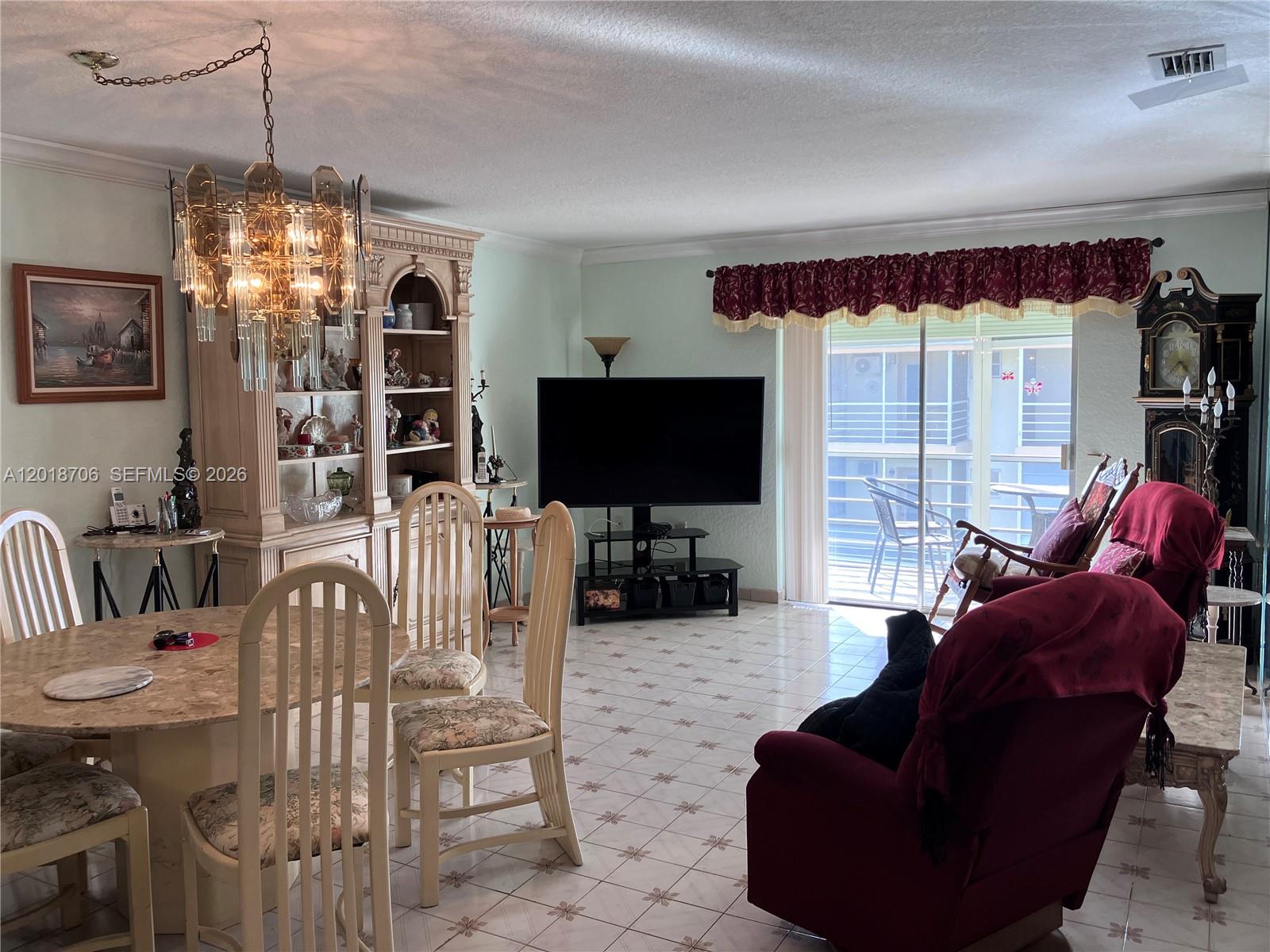 A dining and living area features tile flooring, a chandelier, a hutch, and a balcony — 17090 NE 14th Ave # 312, North Miami Beach FL 33162, NORTH MIAMI BEACH, FL