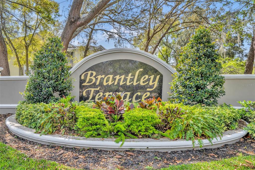 A curved monument sign for Brantley Terrace sits in a landscaped garden with trees — 582 BRANTLEY TERRACE WAY UNIT 304, ALTAMONTE SPRINGS, FL