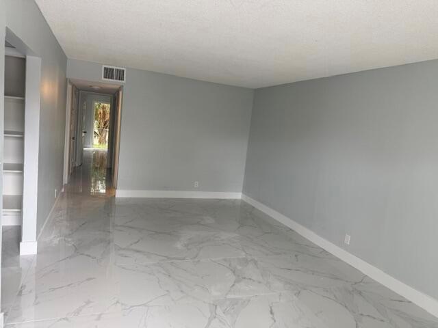 An empty room with gray walls, white baseboards, and large white marble-patterned floor tiles — CORAL SPRINGS, FL