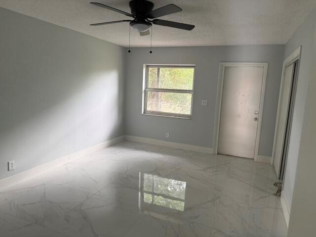 An empty bedroom features light gray walls, white marble-look tile flooring, and a ceiling fan — CORAL SPRINGS, FL