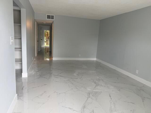 An empty room with gray walls, white baseboards, and polished white marble-look tile flooring — CORAL SPRINGS, FL