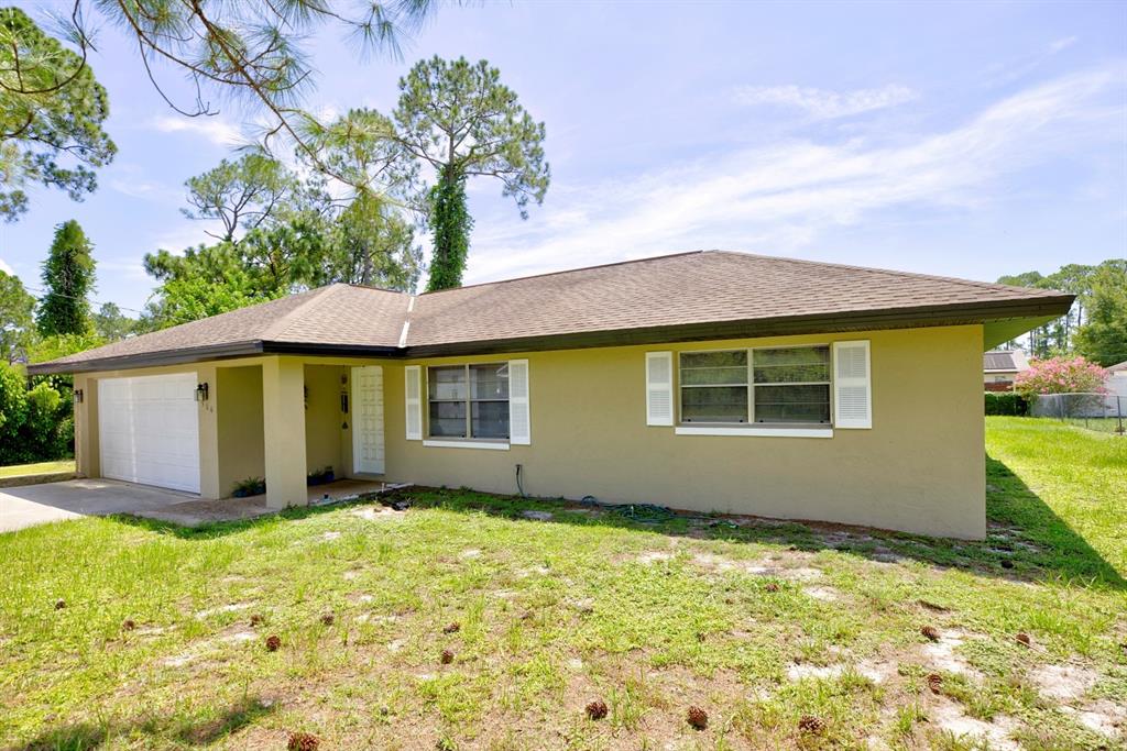 A single-story house with a tan exterior, a white garage door, and a brown roof — 306 LARK TERRACE, SEBRING, FL