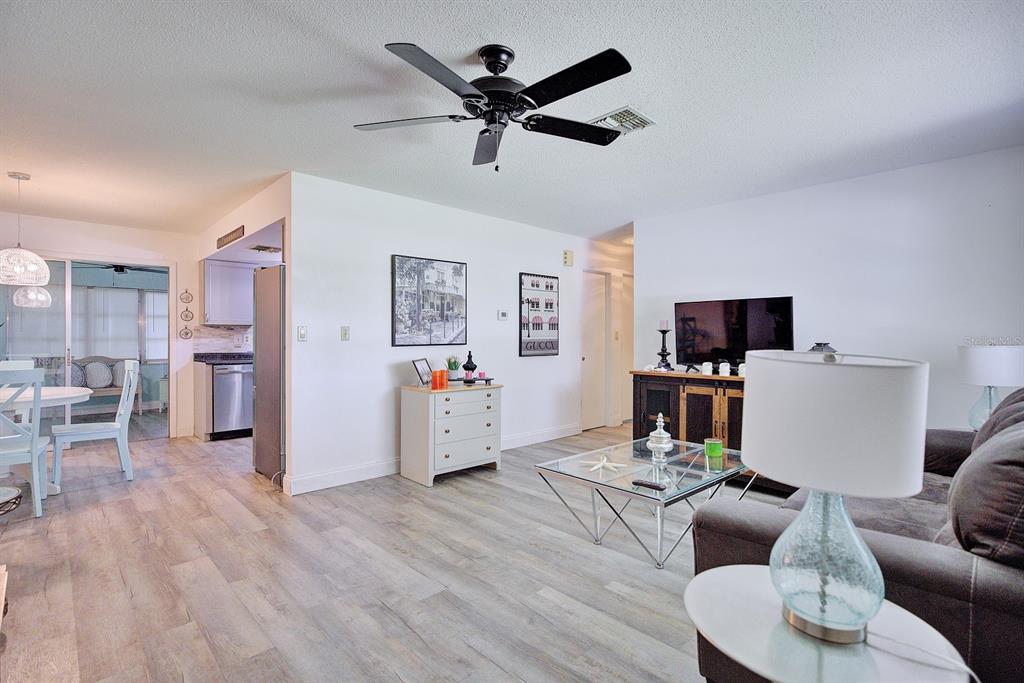 A living room with light wood-look flooring, a ceiling fan, and an adjacent dining area — 306 LARK TERRACE, SEBRING, FL