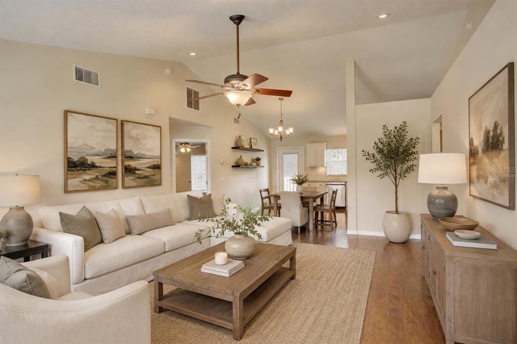 A living room with a sectional sofa, coffee table, and open kitchen in the background — 1360 CHRIS AVENUE, DELAND, FL