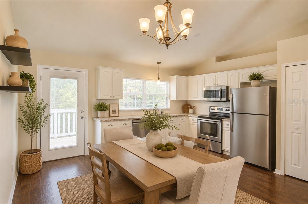 A kitchen and dining area with white cabinets, stainless steel appliances, and a wooden table — 1360 CHRIS AVENUE, DELAND, FL
