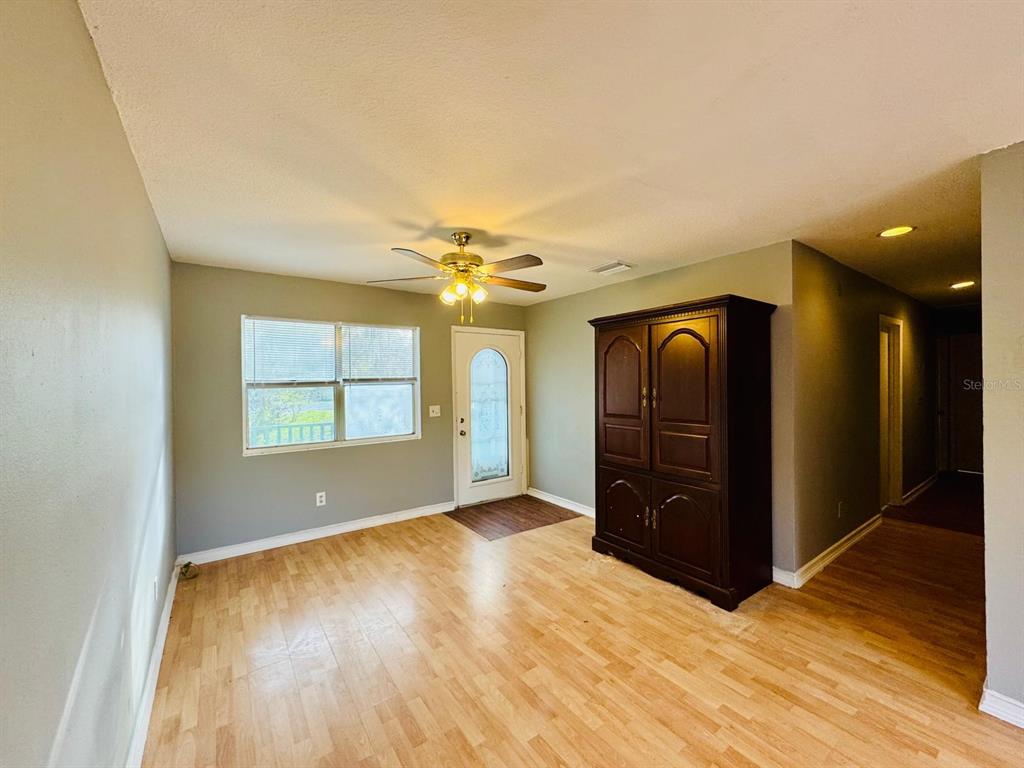 A room with light wood flooring, a ceiling fan, a window, and a large armoire — 12909 LITEWOOD DRIVE, HUDSON, FL