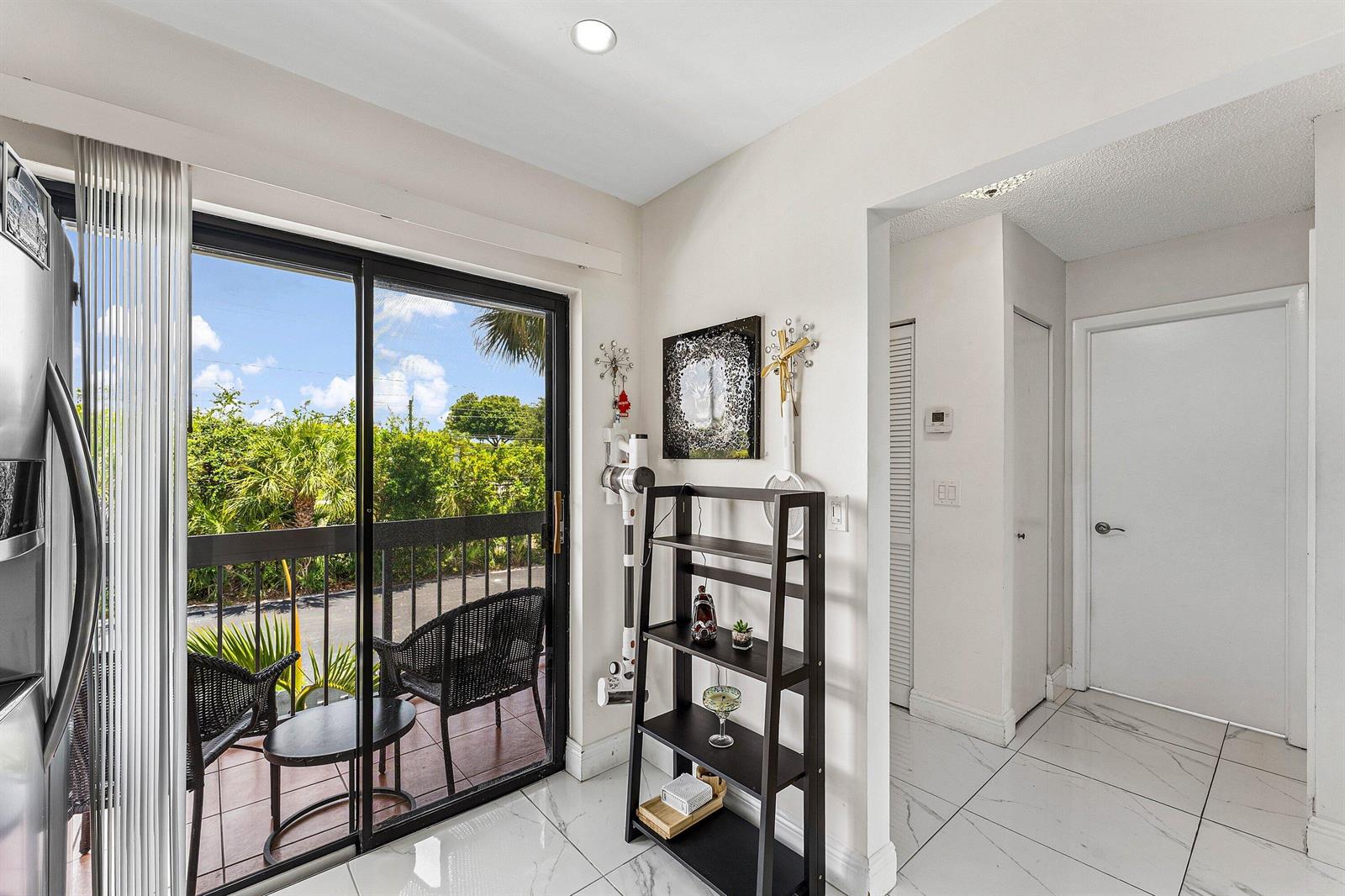 A room with white tile floors, a black shelving unit, and a sliding glass door — 3220 Frederick Boulevard # 49u, Delray Beach FL 33483, DELRAY BEACH, FL