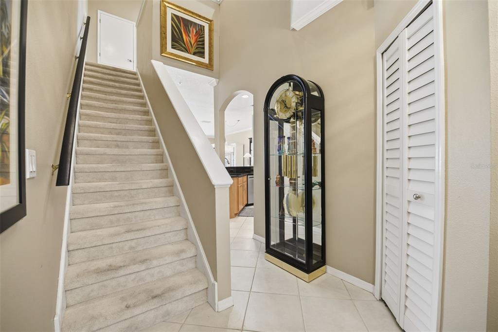 A carpeted staircase leads to an upper level beside a grandfather clock and closet — 11125 KAPOK GRAND CIRCLE, MADEIRA BEACH, FL