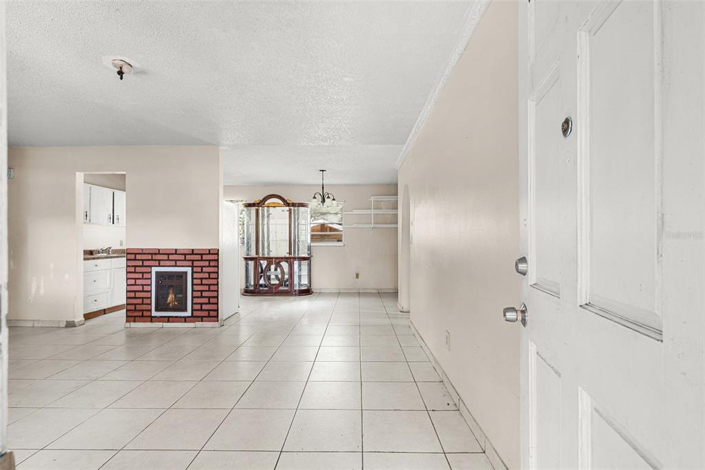 An interior view of a tiled living area featuring a brick fireplace and a curio cabinet — 3805 S TAMPA AVENUE, ORLANDO, FL
