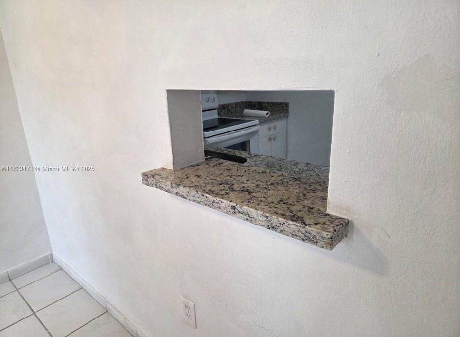 A granite pass-through window connects a white-walled room to a kitchen with white cabinets — 5755 W 20 Ave # 206, Hialeah FL 33012, HIALEAH, FL