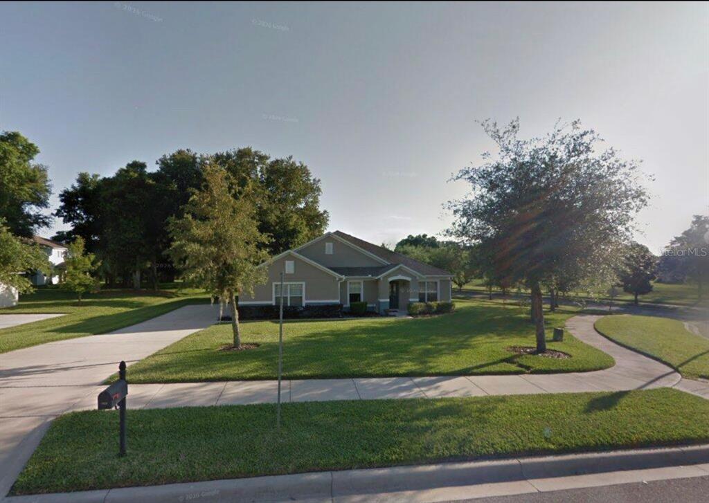 A single-story suburban house with a tan exterior, a concrete driveway, and a grassy lawn — 2626 BREEZY MEADOW ROAD, APOPKA, FL