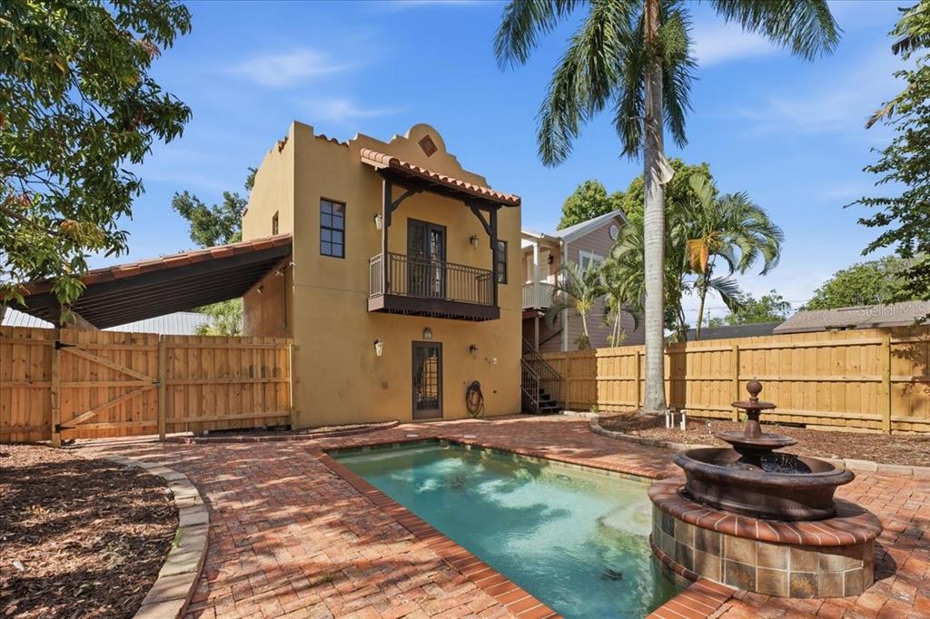 A two-story stucco building with a balcony overlooks a brick-paved pool and fountain area — 1719 7TH STREET, SARASOTA, FL