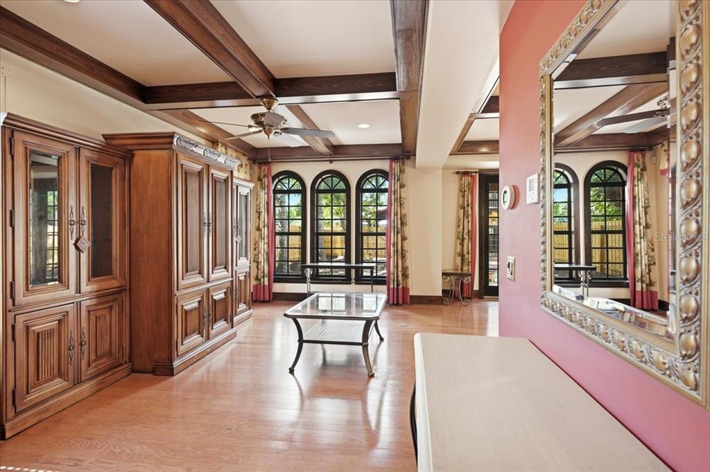 A living room features wood-beamed ceilings, hardwood floors, a large wall unit, and arched windows — 1719 7TH STREET, SARASOTA, FL