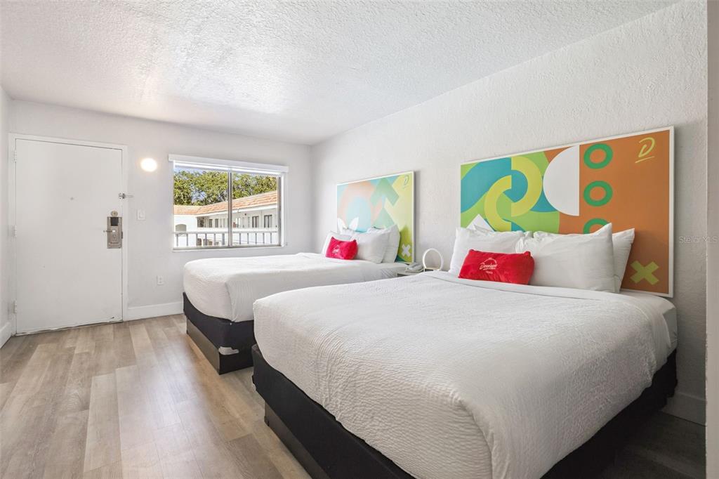 A hotel room features two beds with colorful abstract headboards and light wood-look flooring — 5367 W IRLO BRONSON MEMORIAL HIGHWAY UNIT 1-210, KISSIMMEE, FL