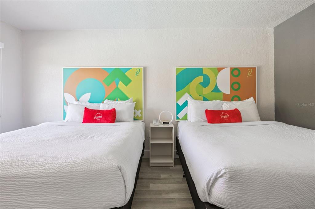 A bedroom features two beds with white linens and colorful abstract headboards separated by a nightstand — 5367 W IRLO BRONSON MEMORIAL HIGHWAY UNIT 1-210, KISSIMMEE, FL