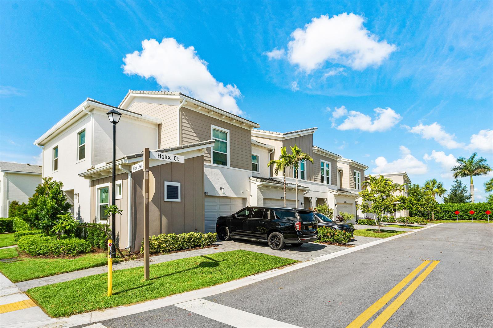 A black SUV is parked in the driveway of a multi-story suburban townhouse complex — 16474 Helix Court, FL 33470, FL