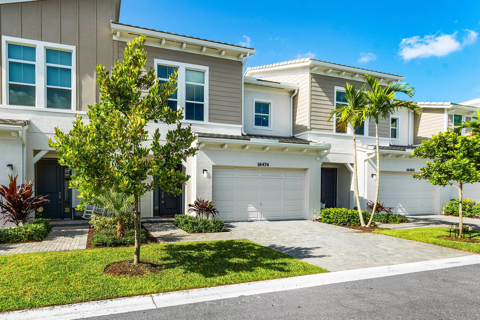A two-story townhouse exterior features a white garage, tan siding, and a paved driveway — 16474 Helix Court, FL 33470, FL
