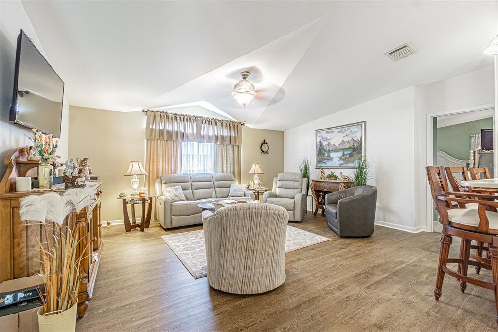 A living room features light-colored furniture, wood-look flooring, and a vaulted ceiling with a fan — 37349 GILL AVENUE, ZEPHYRHILLS, FL