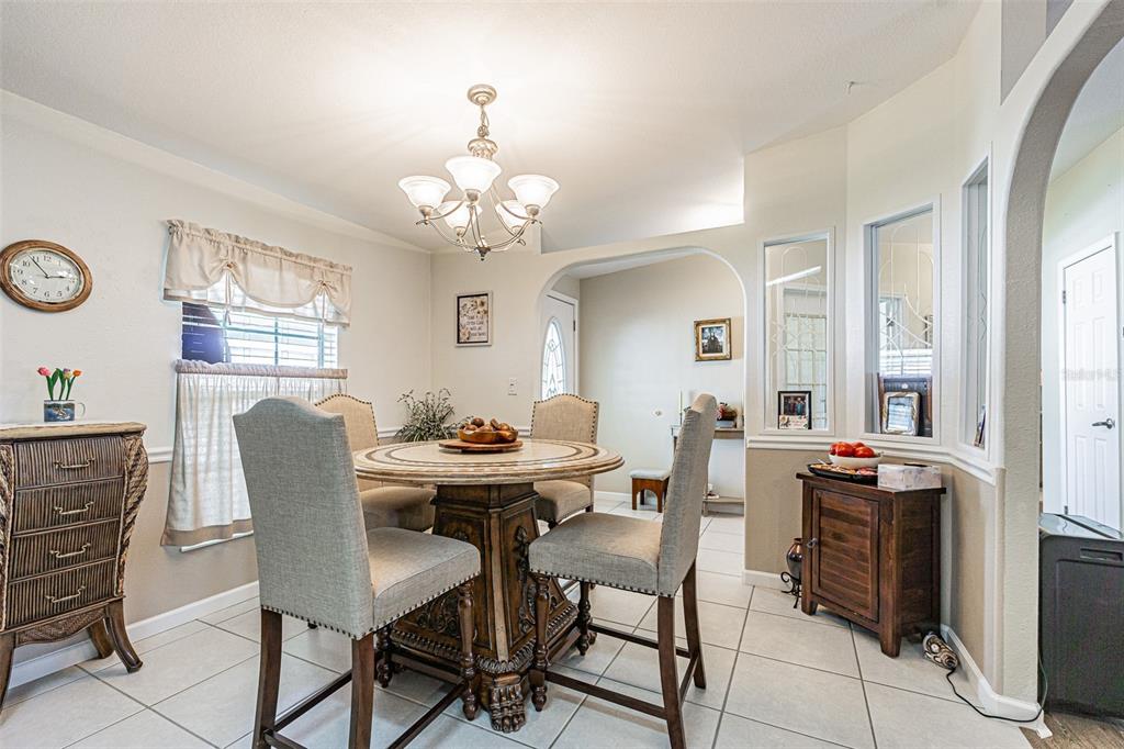 A dining room features a round table with four upholstered chairs and tile flooring — 37349 GILL AVENUE, ZEPHYRHILLS, FL