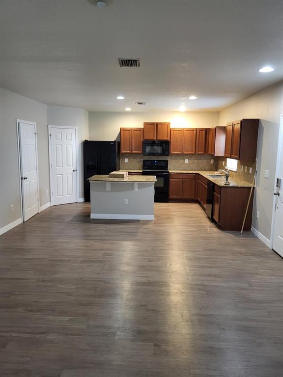 A kitchen features wood cabinets, granite countertops, a central island, and wood-look flooring — 4717 CHATTERTON WAY, RIVERVIEW, FL