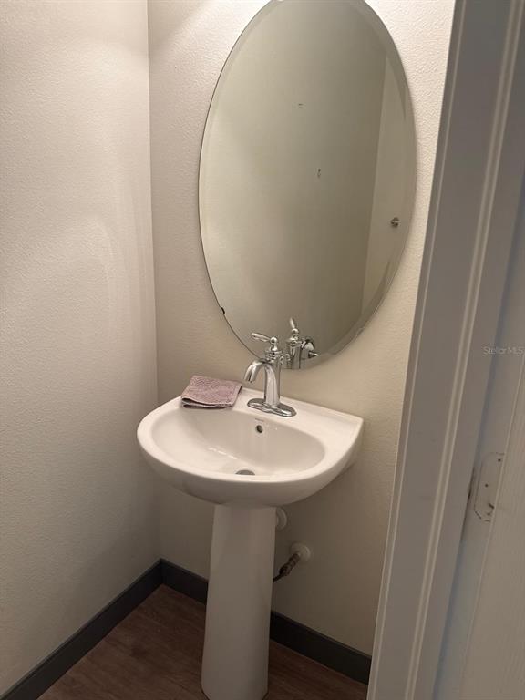 A pedestal sink with a chrome faucet sits below an oval mirror in a small bathroom — 4717 CHATTERTON WAY, RIVERVIEW, FL