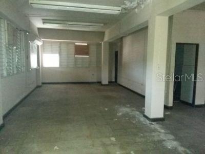 An empty commercial space features white walls, fluorescent ceiling lights, and a concrete floor — 10 VELA ST., SAN JUAN, PR