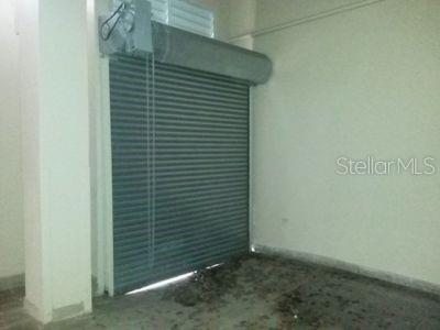 An interior view of a garage featuring a metal roll-up door and a concrete floor — 10 VELA ST., SAN JUAN, PR