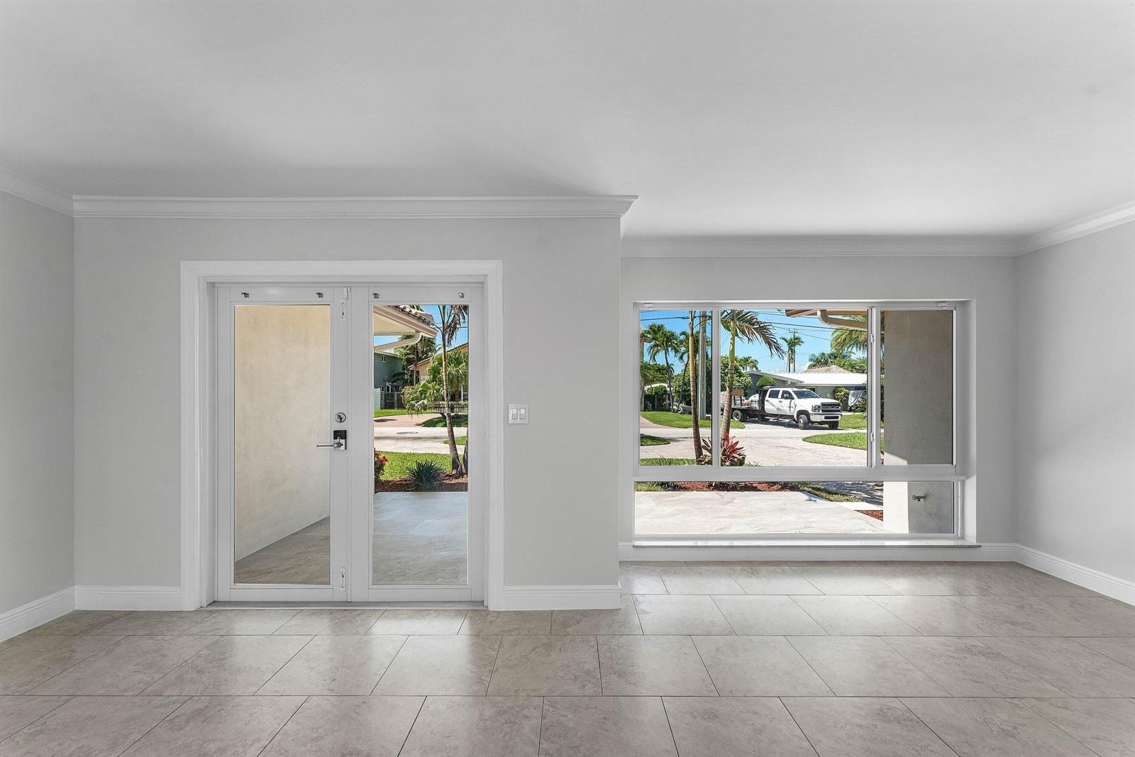 A room with light-colored tile flooring, white walls, a glass door, and a large window — 1525 SE 6th Street, Deerfield Beach FL 33441, DEERFIELD BEACH, FL
