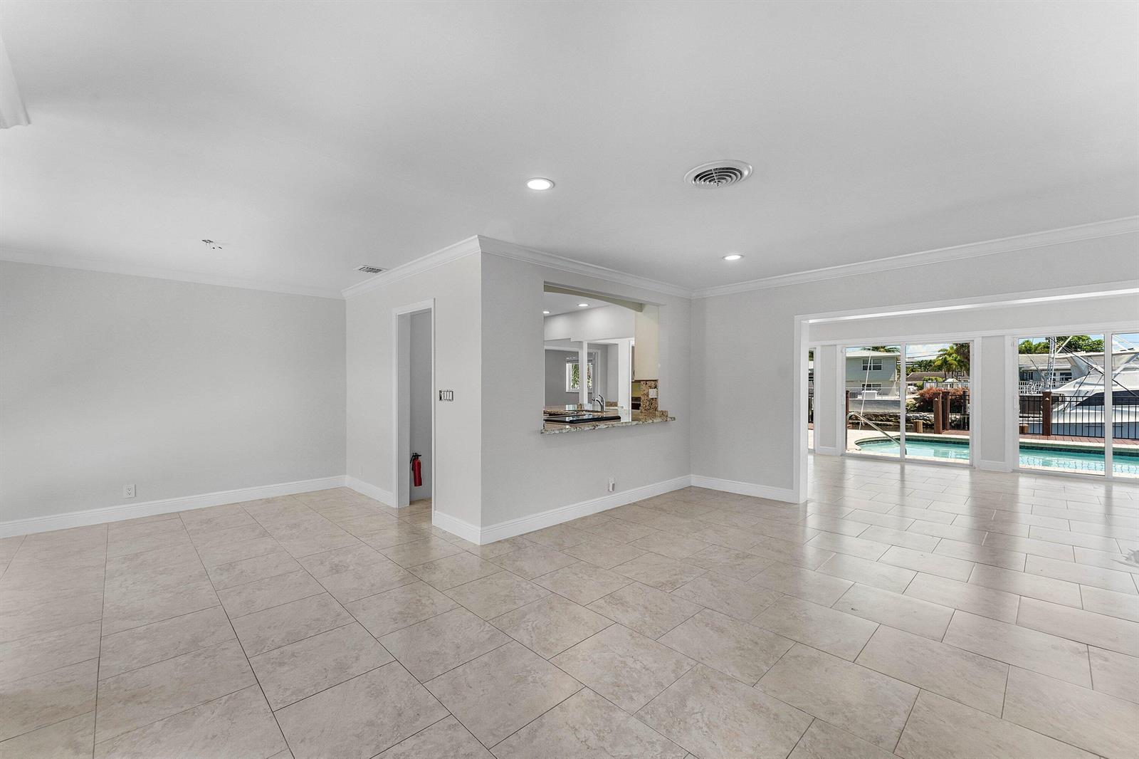 An open living area with tile floors, a kitchen pass-through, and sliding doors to a pool — 1525 SE 6th Street, Deerfield Beach FL 33441, DEERFIELD BEACH, FL