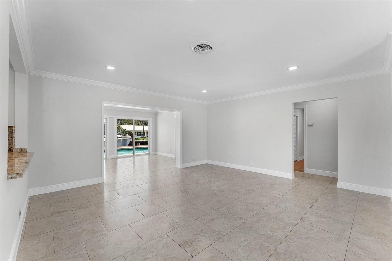 An open-concept living area features light tile flooring, recessed lighting, and a view of a pool — 1525 SE 6th Street, Deerfield Beach FL 33441, DEERFIELD BEACH, FL