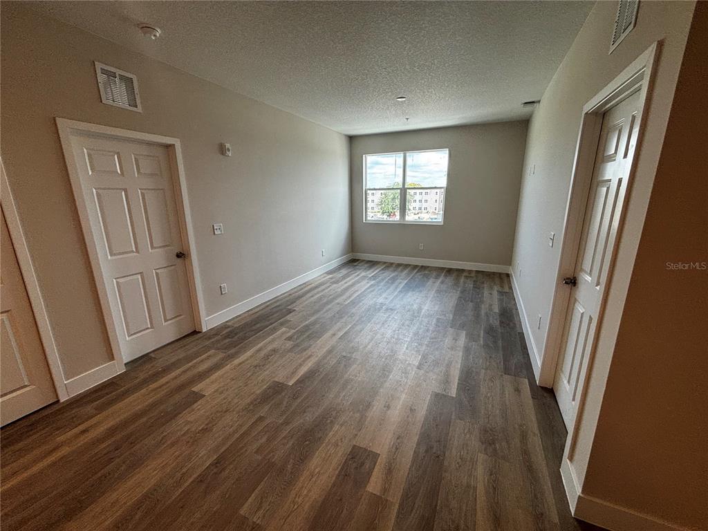 An empty room features light-colored walls, wood-look flooring, two white doors, and a single window — 4424 S TEXAS AVENUE UNIT 304, ORLANDO, FL