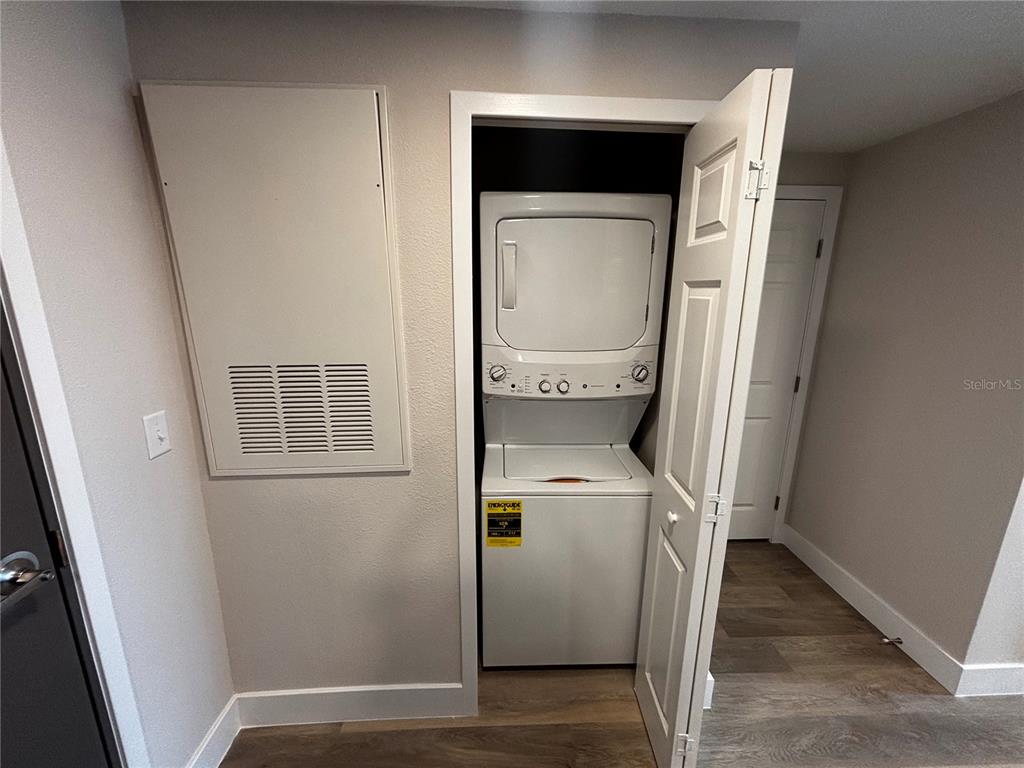 A laundry closet with a stacked washer and dryer sits next to a wall vent — 4424 S TEXAS AVENUE UNIT 304, ORLANDO, FL